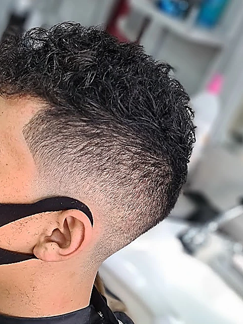 Fade alto con el rizo natural arriba, visto de perfil