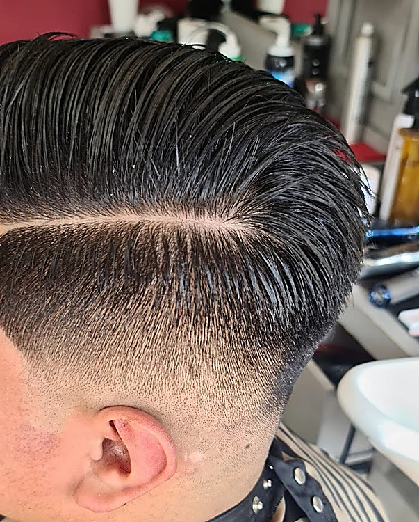 Corte con raya marcada, cabello peinado hacia un lado y fade bajo, visto de perfil